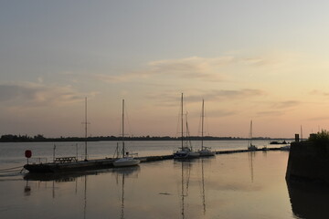 Fototapeta na wymiar Bateaux à voile le long du ponton, au coucher du soleil, à Bourg