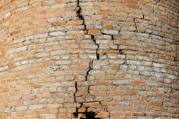 A crack in a brick wall of an old building. The antique red brickwork is beginning to deteriorate.
