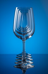 Five wine glasses in row concentric on blue background