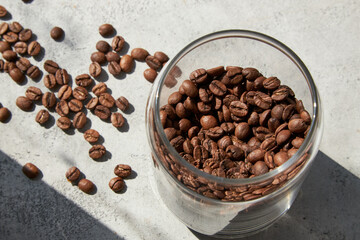 Open glass jar with coffee beans in sun light, top view.