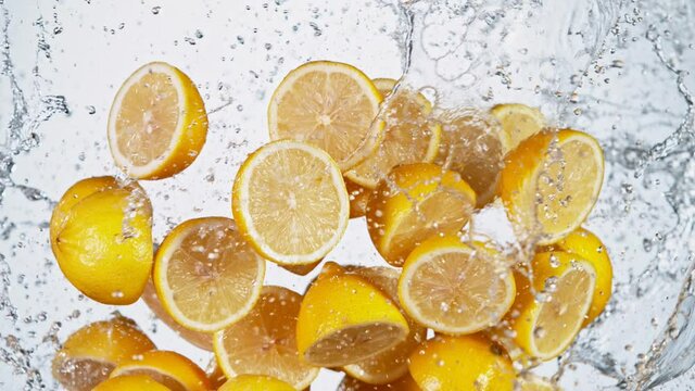 Super slow motion of sliced fresh lemons with water splash flying in the air. Filmed on high speed cinema camera, 1000 fps.