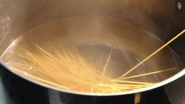 the chef throws spaghetti into boiling water