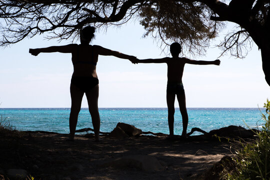 silhouette of two people with a crystalline sea in the background near the beach of Cala Liberotto, Sardinia.