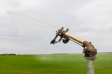 Sprinkler watering agricultural field in the sun Irrigation plant in agriculture under bright sunlight . Agriculture watering spray field.