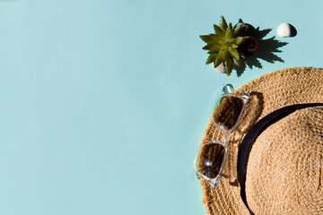 straw hat and sunglasses on blue color background, summer vacations flat lay, copy space