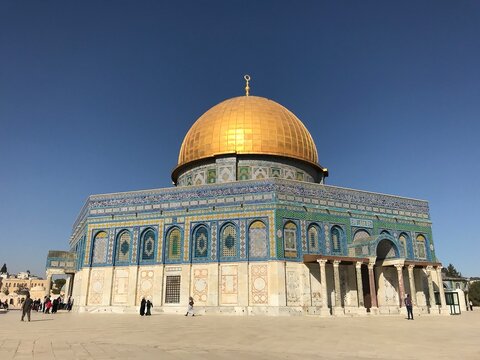 View of Al Aqsa intricate design with sun reflection on golden dome and blue sky