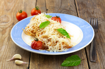 Pasta with tomato sause, cherry tomatoes and basil on wooden background