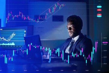 businessman working with a laptop in the office at night with several screens. Analyzing data 