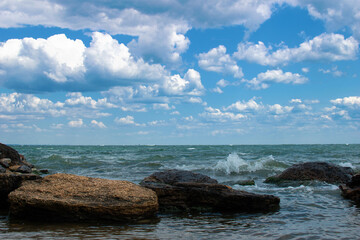 Stormy sea or ocean with rocks and dramatic cloudy blue sky
