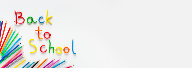 Plasticine inscription "Back to school" and multicolored pencils on a white background