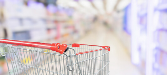 empty red shopping cart in supermarket aisle