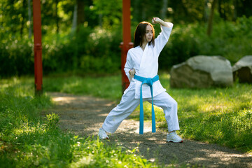 Young Woman in Kimono practicing karate, Japanese martial arts outdoors. Early foggy morning