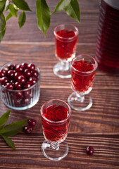 glasses of cherry brandy liqueur with ripe berries on wooden table