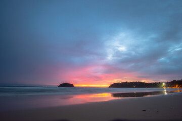 Obraz premium beautiful sunset behind Pu island at Kata beach Phuket. a lot of tourists relax on the beach during sunset..