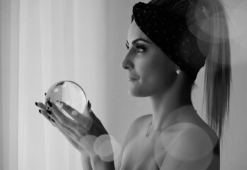 Junge Frau in Gedanken vertieft mit der Glaskugel und natürlichem Sonnenlicht