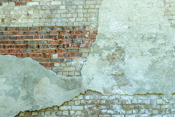 Gray plastered old brickwall with chipped stucco pieces. Grunge red and white brick wall with damaged surface background