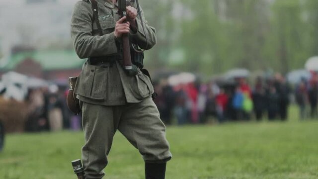 Bearded soldier in uniform of Wehrmacht of German army during World War II holds rifle gun in hands and runs during reconstruction of invasion to USSR 22 June 1941 in Soviet Union. Rain