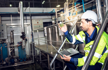 Caucasian engineer man using computer notebook for checking the quality of  herbal drinks, Which contain Basil Seed, on the conveyor belt, to beverage production industry concept.