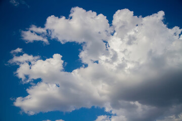 Cumulus clouds against a dark blue sky.
