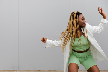 Young adult black woman with long blond braided hair dancing. Copy space.