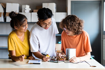 Multiracial group of high school students learn electronics together.