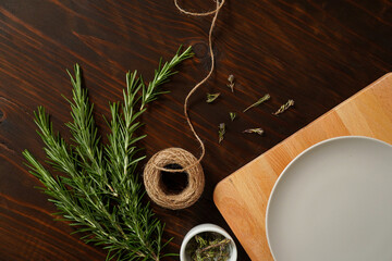 Fresh rosemary bound on brown  wooden board with twine and dry thyme flowers. Healthy organic concept. Aroma herb for cooking