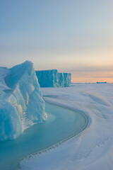Ice berg on frozen sea at sunrise