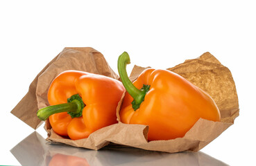 Two organic bell peppers on craft paper, close-up, isolated on white.