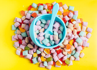 Children's tableware silicone bowl with spoon. Serving baby food, kid dishware.blue silicone bowl and spoon are in a heap of sweets and marmalade. bright, colorful photo flatly