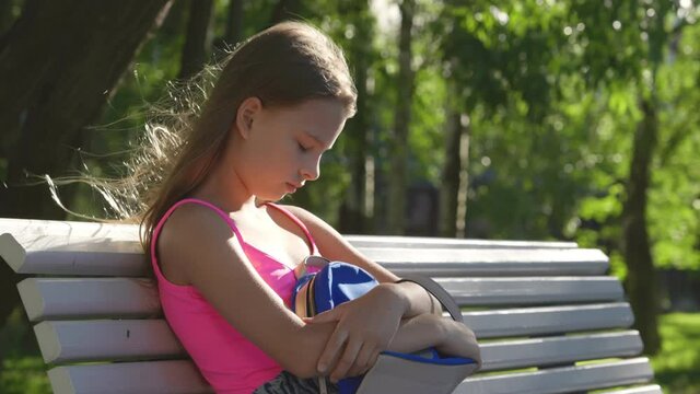 Sad lonely teenage girl sitting on bench and crying in park