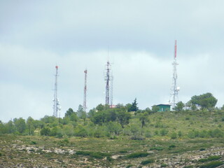 Telecommunication antennas on top of a mountain, with cloudy sky