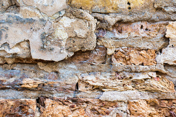 Old cracked weathered plastered brick wall background texture. Dirty peeled plaster wall with falling off flakes of paint