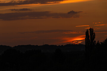 Colorful sunset on a warm summer evening over the rolling hills in Limburg. The sky showed amazing colours which gives a natural contrast to the green colours of the  forest and meadow