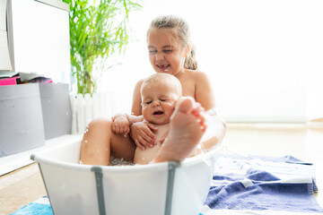 Caucasian boy and girl having fun in a bathtub in the middle of the living room. Fun bath concept.