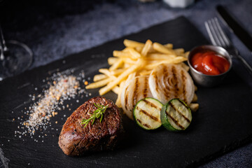 tenderloin steak on black stone plate with french fries