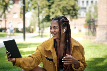 Young woman with cool hair using a tablet in a park.