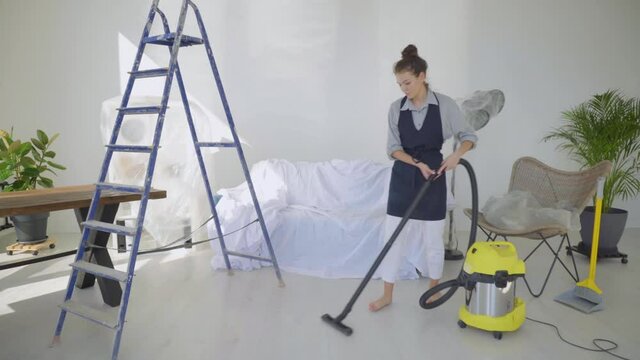 Housework and cleaning concept. Caucasian young woman or housewife with vacuum cleaner at home. Woman is vacuuming a floor during home repair.
