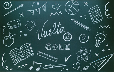 Blackboard written with chalk with spanish message and school supplies. Back to school concept