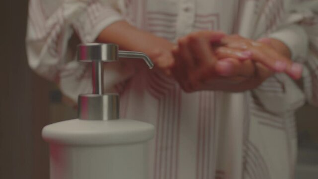 Close up of African American female washing her hands with soap. Preventing decease by thorough hand washing.