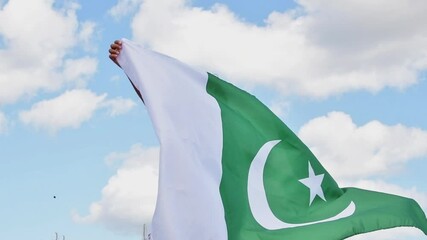 Girl waving flag of Pakistan outdoors over blue cloudy sky and golden wheat. Happy independence day