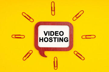 On a yellow background, paper clips and a mental plaque with the inscription - Video Hosting