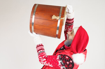 Santa Claus drinks from a large wooden bucket.