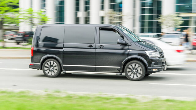 Black Volkswagen Multivan T6 riding at the city street