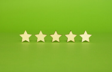 Wooden five-star shapes on a green background. The best customer experience concept. Rating of different business and hospitality services.
