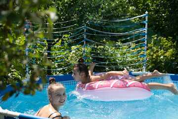 Happy children swim in swimming pool on sunny summer day, vacation