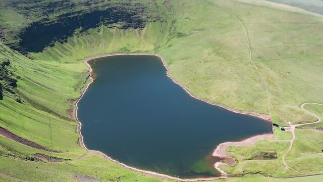 Aerial view of a lake at the foot of large cliffs (Llyn y Fan Fach)