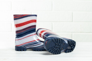 Children's rubber boots in blue and red stripes in white background.Children's rain shoes. Boots for autumn and rain.