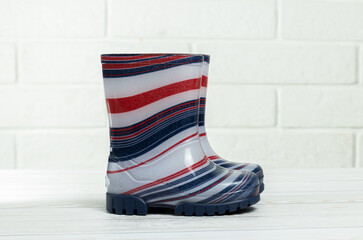 Children's rubber boots in blue and red stripes in white background.Children's rain shoes. Boots for autumn and rain.