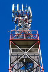 Top of telecommunication tower with antennas and transmitters, clear blue sky background