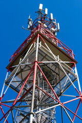 Top of telecommunication tower with antennas and transmitters, clear blue sky background